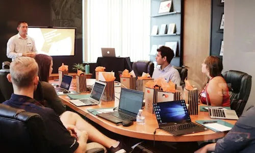 The team gathered around a meeting table with laptops