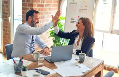 Two colleagues sharing a high five at a desk
